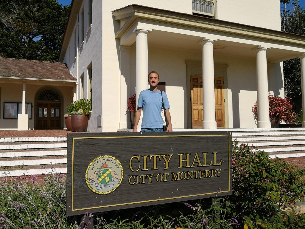 Farid Kayali standing behind the City Hall sign in Monterey. 